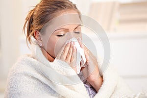 Young woman having flu blowing her nose