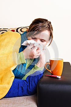 Young woman having flu, blowing her nose