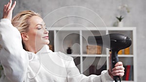 Young woman having fun and dancing, drying her hair with a hairdryer at home.