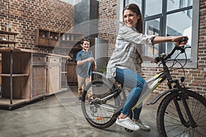 Young woman having fun with her little son and riding bicycle