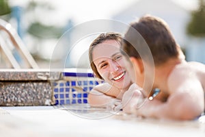 Young woman having fun with her son at resort pool on vacation