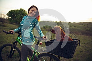 Young woman having fun near countryside park, riding bike, traveling with companion spaniel dog