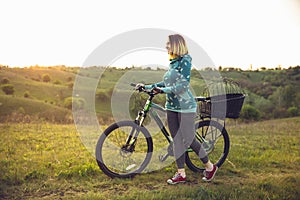 Young woman having fun near countryside park, riding bike, traveling at spring day