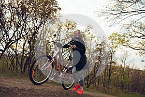 Young woman having fun near countryside park, riding bike, traveling at spring day