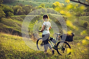 Young woman having fun near countryside park, riding bike, traveling at spring day