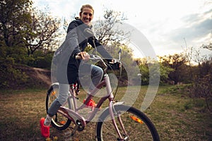 Young woman having fun near countryside park, riding bike, traveling at spring day