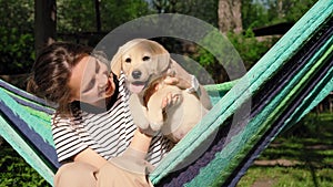 Young woman having fun playing with her little cute labrador puppy