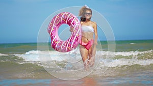 Young woman having fun with toy Inflatable ring donut on the beach.