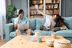 Young woman having fun and trying to distract her boyfriend working from home online on laptop. Freelance man work on a computer