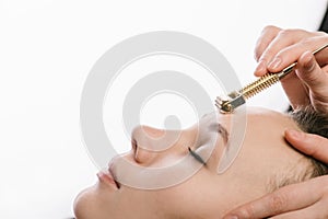 Young woman having a gua sha face massage at asian beauty clinic. Side view