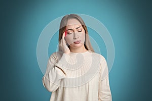 Young woman having headache on light blue background
