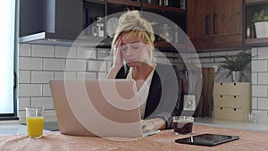 Young woman having headache while working on laptop