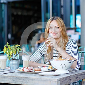 Young woman having healthy breakfast in outdoor cafe