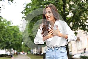 Young woman having heart attack on city . Space for text