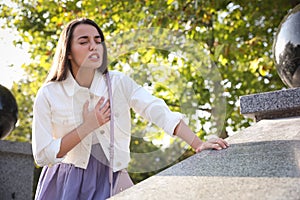 Young woman having heart attack in park