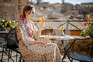 Young woman having lunch with pizza and wine at outdoor restaurant in Siena town