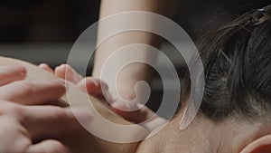 Young woman having massage in spa salon. Action. Close up of woman relaxing during back, neck, and head massage lying on