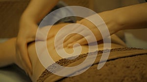 Young woman having massage in spa salon. Close-up of woman relaxing during back massage lying on massage table in slow