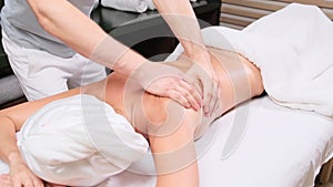 Young woman having massage in spa salon. Close-up of woman relaxing during back massage lying on massage table in slow