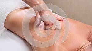 Young woman having massage in spa salon. Close-up of woman relaxing during back massage lying on massage table in slow