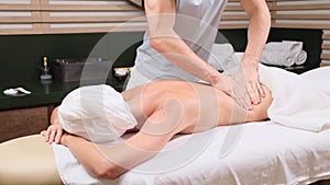 Young woman having massage in spa salon. Close-up of woman relaxing during back massage lying on massage table in slow