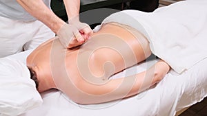 Young woman having massage in spa salon. Close-up of woman relaxing during back massage lying on massage table in slow