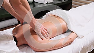 Young woman having massage in spa salon. Close-up of woman relaxing during back massage lying on massage table in slow