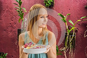 Young woman having a mediterranean breakfast, eats Healthy tropical breakfast, smoothie bowl with tropical fruits