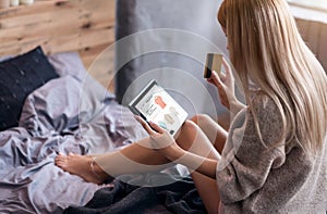 Young woman having online shopping in bedroom