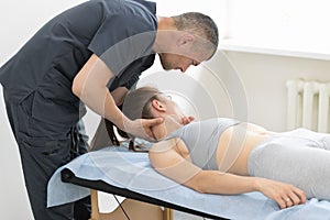 Young woman having osteopathy treatment in the cabinet - vertebra reduction