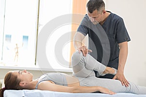 Young woman having osteopathy treatment - pushing on the knee