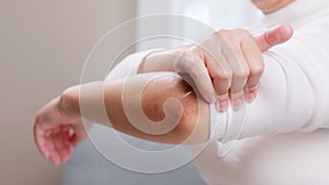 Young woman having pain in her elbow and using hand for self-massage to relieve aches and pains.