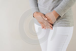 Young woman having painful stomachache with hands holding pressing her crotch lower abdomen.