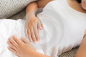 Young woman having painful stomachache lying on sofa at home