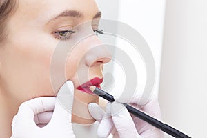 Young woman having permanent makeup on her lip