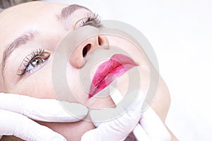 Young woman having permanent makeup on her lip