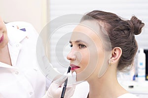 Young woman having permanent makeup on her lips