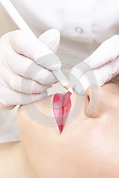 Young woman having permanent makeup on her lips at the beauticians salon.