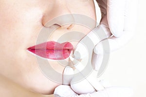 Young woman having permanent makeup on her lips at the beauticians salon.