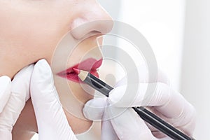 Young woman having permanent makeup on her lips at the beauticians salon.