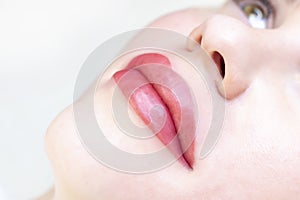 Young woman having permanent makeup on her lips at the beauticians salon