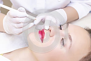 Young woman having permanent makeup on her lips at the beauticians salon