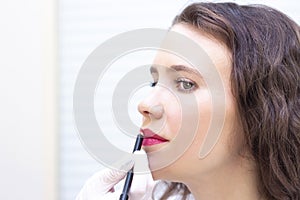 Young woman having permanent makeup on her lips at the beauticians salon.