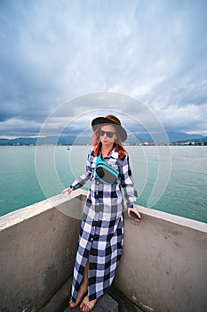 Young woman having a rest at the seacoast. Black Sea landscape. Front view. sunglasses and small bag. Travel and vacation.