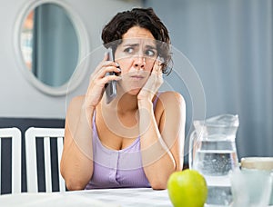 Young woman having toothache, sitting and using smartphone