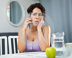 Young woman having toothache, sitting and using smartphone