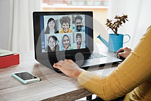 Young woman having video call with her colleagues using laptop computer app - Focus on left hand
