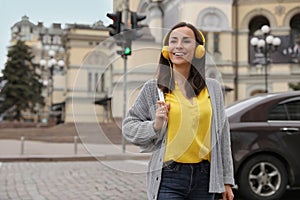 Young woman with headphones crossing street