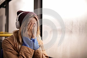 Young woman with headphones listening to music in public transport