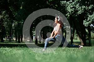 young woman with headphones performing squats outdoors.